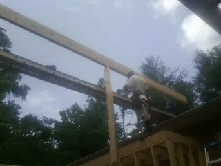 Carpenter setting a ridge beam over a new addition frame — Ice Dam Removal by Roofing Brothers in Hubbardston