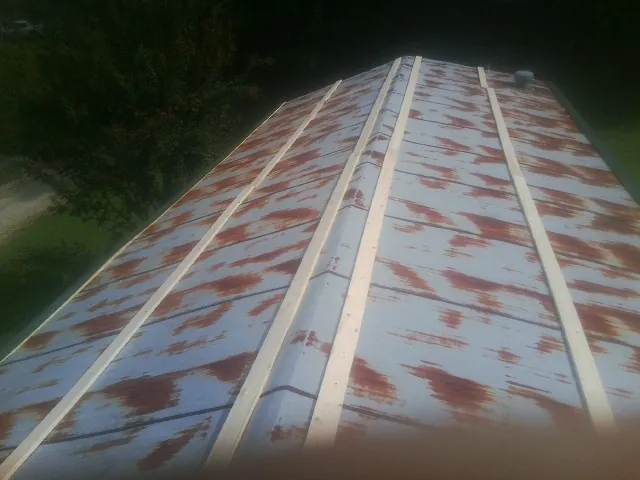 Rusted metal roof panels with new wood purlins before replacement — Storm Damage Roof Repair in Hubbardston by Roofing Brothers