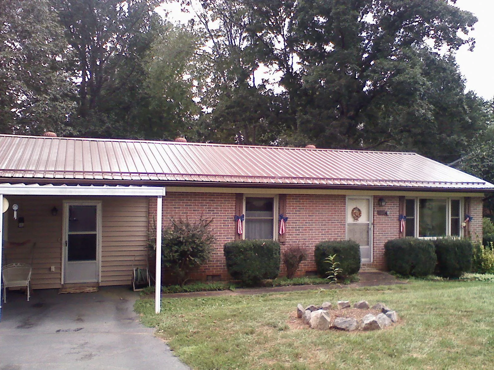 Bronze metal roof and carport on a brick ranch home — Roof Repair work by our crew in Hubbardston